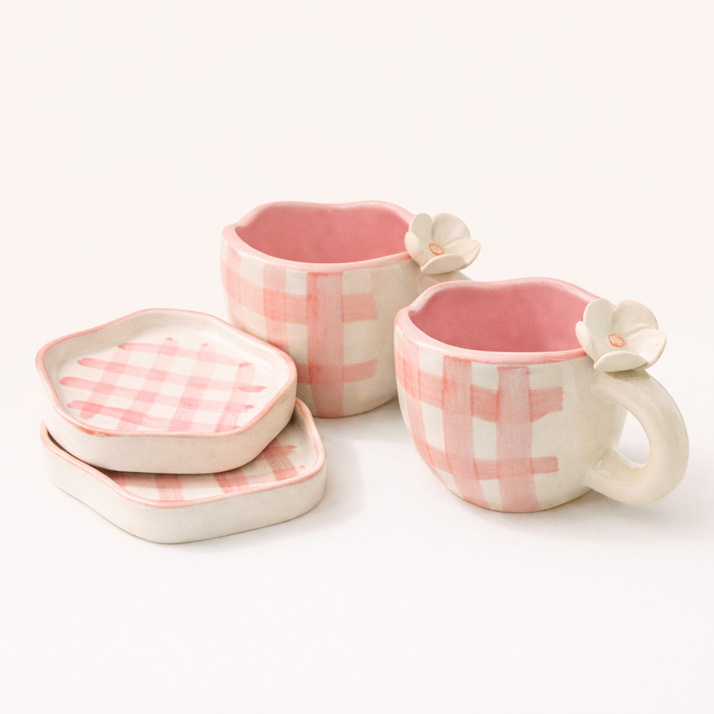 Set of pink and white checkered ceramic mugs and bowls on a white background